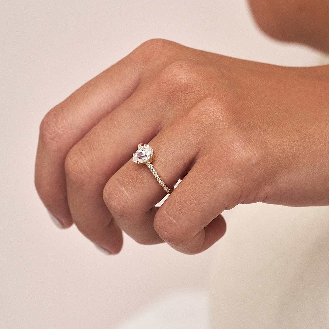 This is the Charles Engagement Ring in 18k yellow gold with an elegant pear-cut lab-grown diamond, framed by pavé diamonds on the ring shoulders, from brand Veynou.
